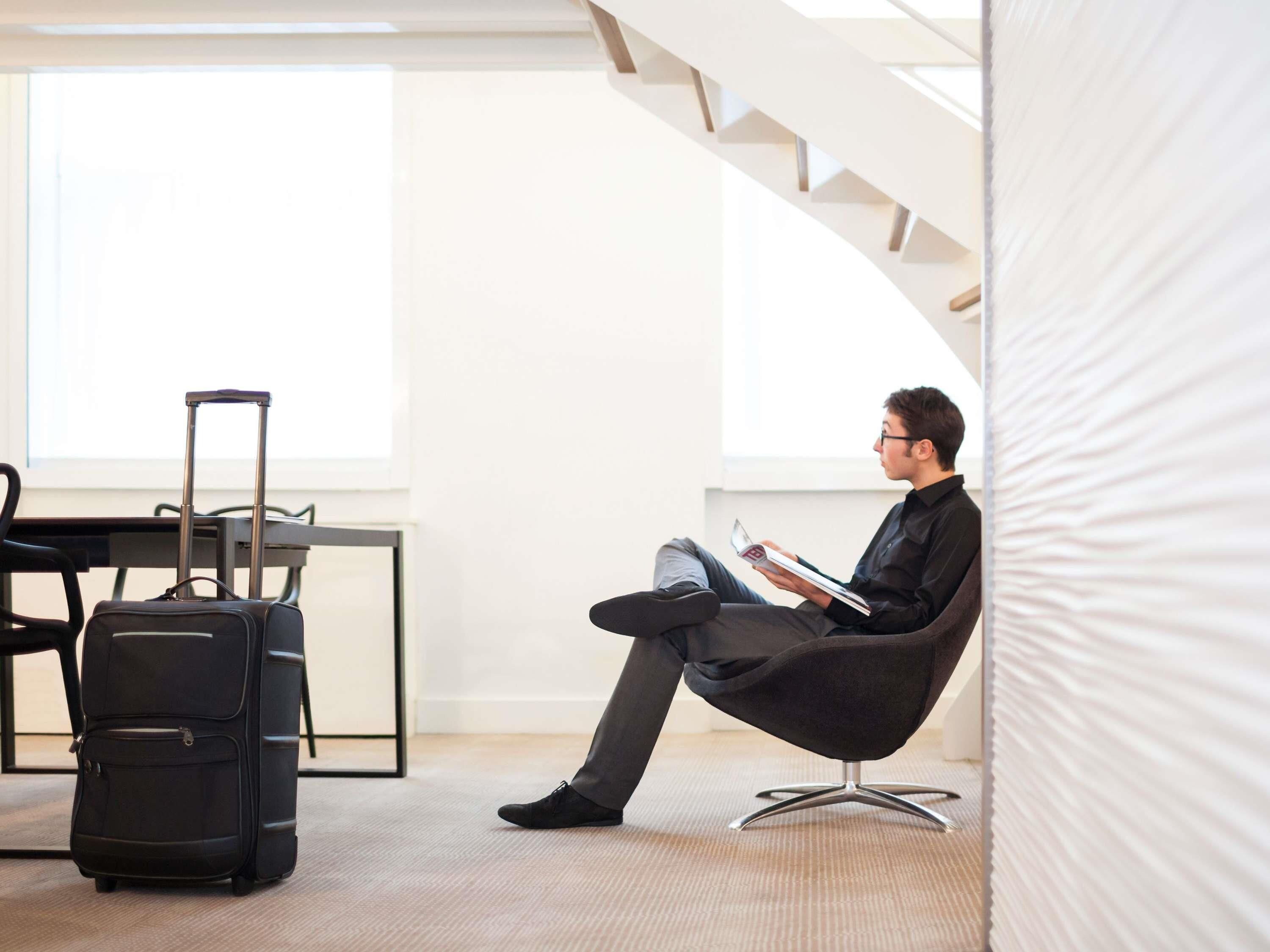 A modern hotel room with a large window, a staircase, a desk, and a chair.