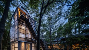 A modern, multi-level cabin with a staircase leading to the upper floor, surrounded by dense forest. - ThinkStay Mt. (Kobe)