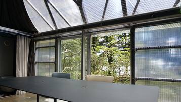 A modern room with a large table, two chairs, and large windows with a view of trees.