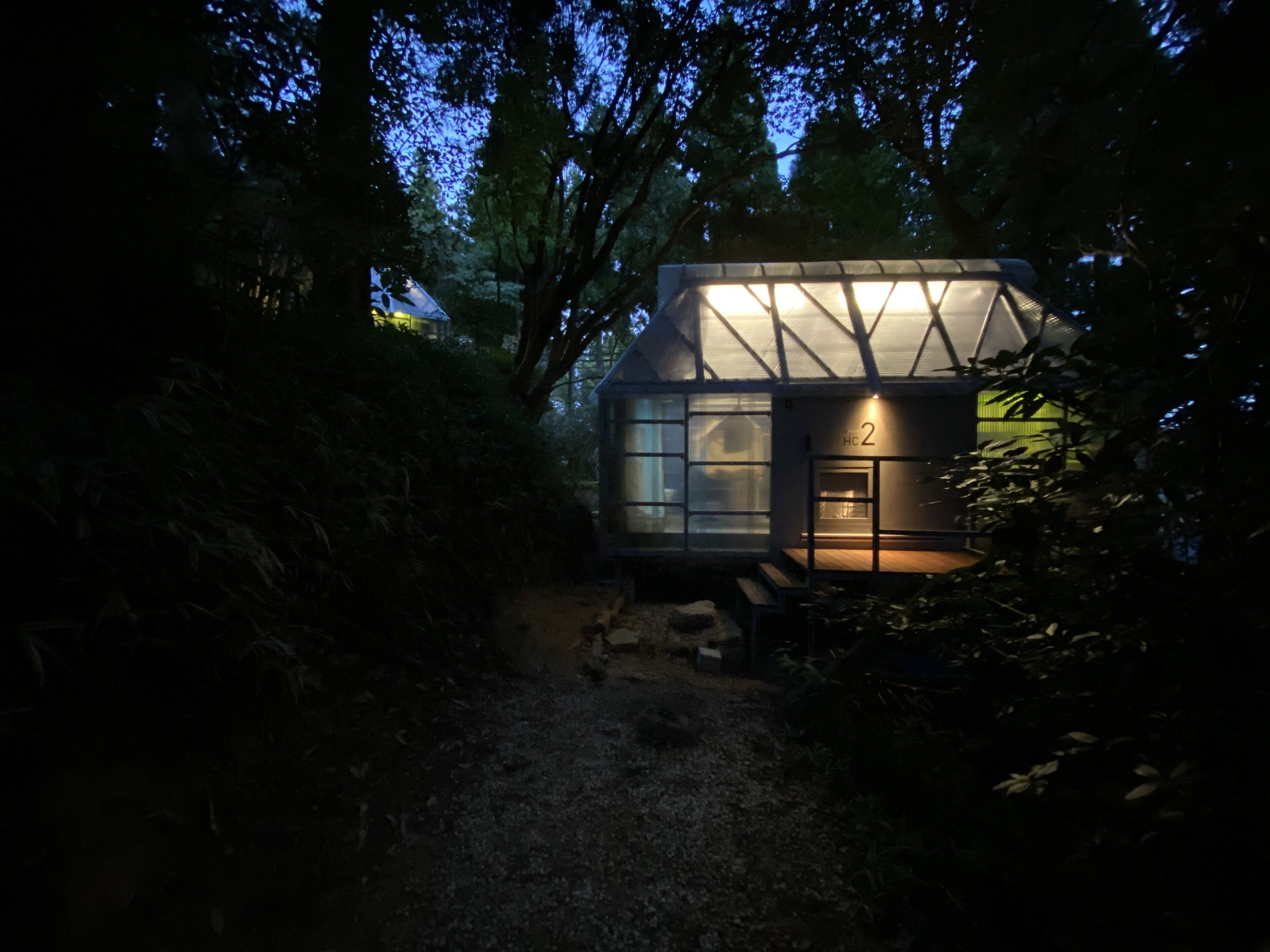Et afsides beliggende, moderne hus med en glasfacade, omgivet af frodig vegetation.