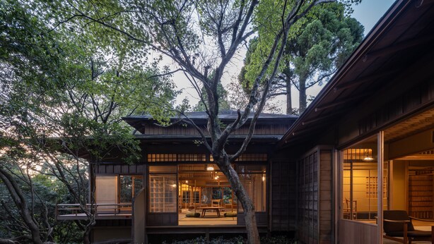 A traditional Japanese-style house with a wooden exterior, large sliding doors, and a garden area with dense foliage and a tree. - ThinkStay Mt. (Kobe)