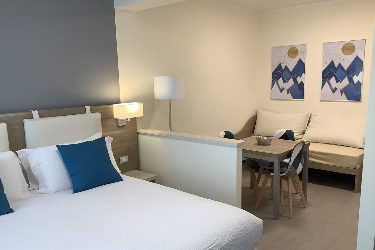 Una habitación de hotel con una cama, un escritorio, una silla y un sofá.