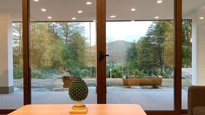 Ein Zimmer mit einer großen Schiebeglasdoor, die zu einem Garten mit einer hölzernen Bank und einer Ananas-Skulptur auf einem Tisch führt.