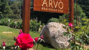 Uma placa de madeira com o texto 'ARVO RESIDENCE SILA' indicando uma área residencial.