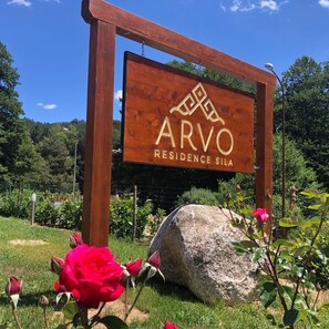 Ein Holzschild mit dem Schriftzug "ARVO RESIDENCE SILA", das auf einen Wohnbereich hinweist.