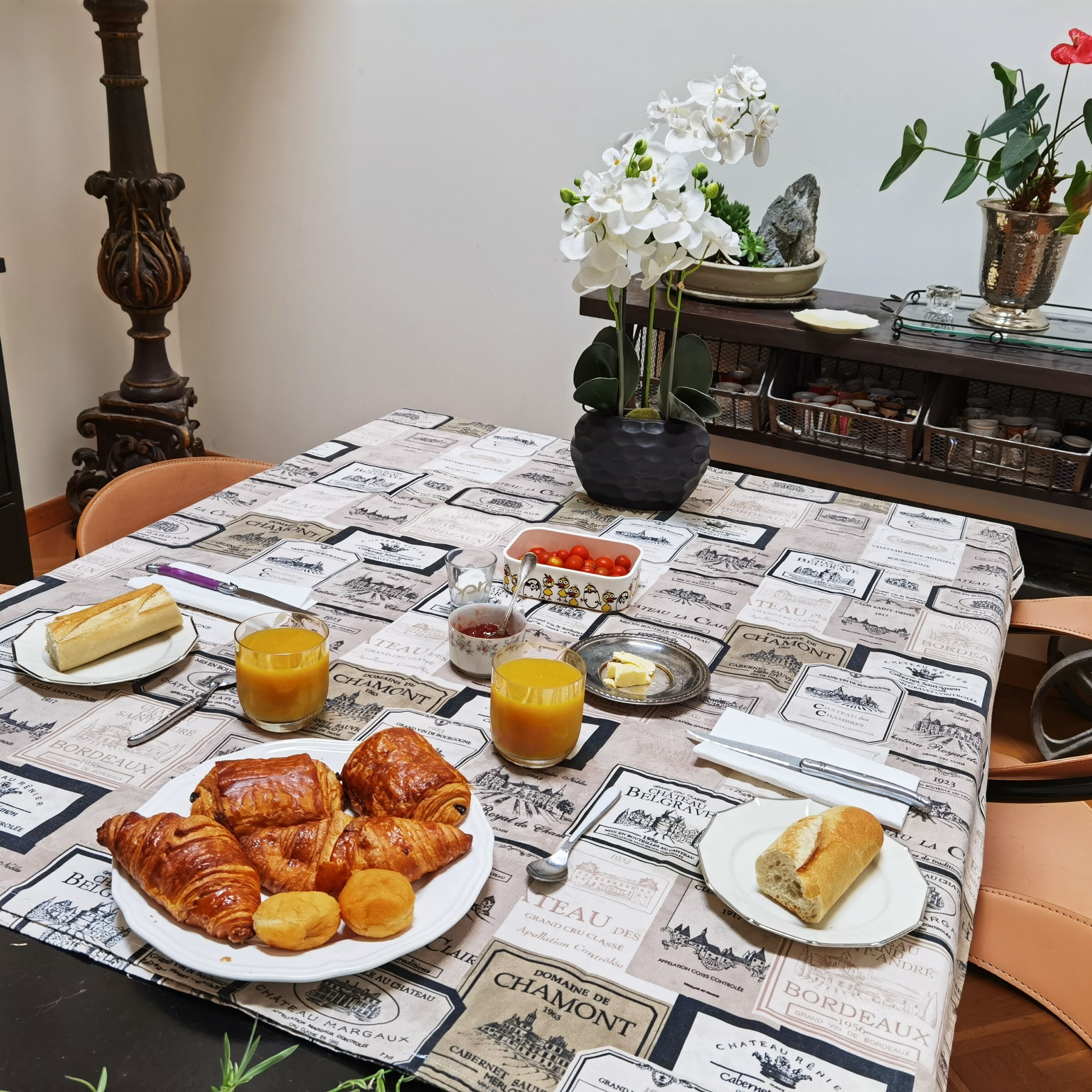 Ein Frühstückstisch mit Croissants, Orangensaft und einer Tomatenschale.