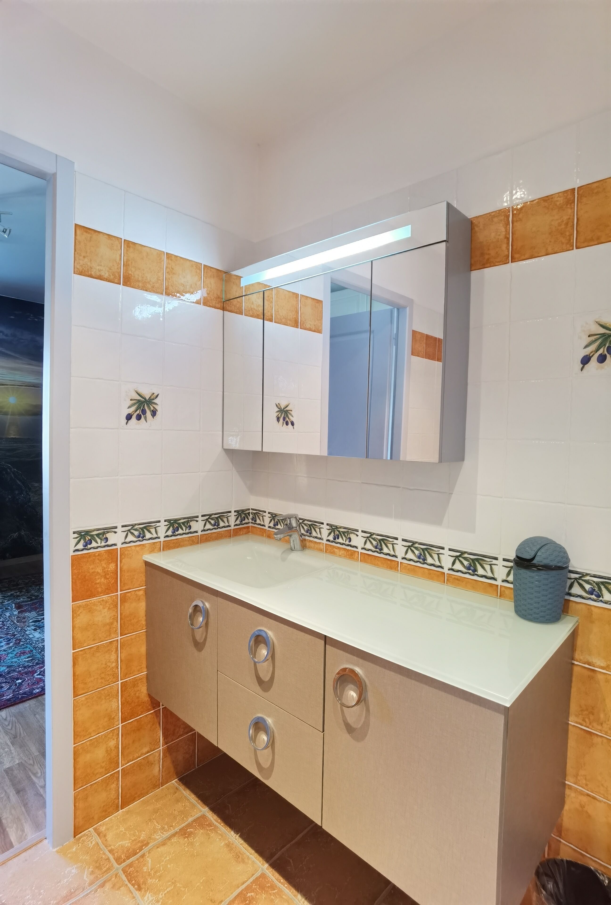A bathroom with a white sink, a mirror, and a cabinet with drawers.