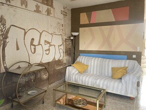 Experience eclectic style in this unique room, featuring a striking graffiti artwork and a modern sofa.