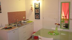 A compact kitchen with a sink, stove, and a dining table with chairs.