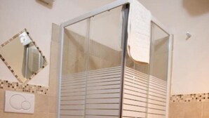 A bathroom with a glass-enclosed shower, a toilet, and a sink.