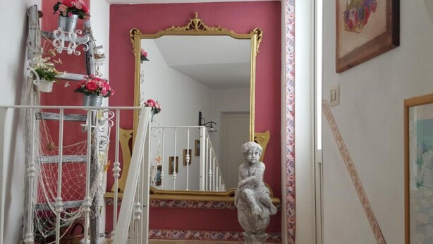 A room with a large mirror, a statue, and a staircase.
