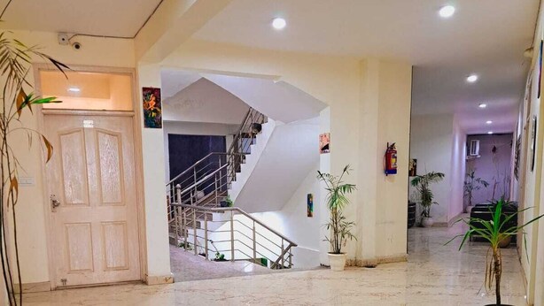 Un vestíbulo amplio con piso de mármol, una escalera y plantas en macetas.