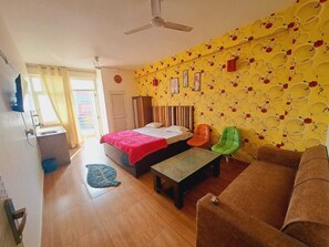 A bedroom with a bed, a desk, a chair, and a sofa. - Hotel Noida Stay (Noida)