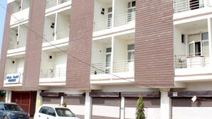 Un edificio de varios pisos con balcones, una señalización de hotel y automóviles estacionados.
