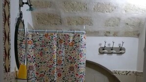 A bathroom with a bathtub, a sink, a toilet, and a shower curtain. - Quad room (Monopoli)