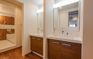 Bathroom features two sinks, a large mirror, and a shower area with a handheld showerhead.