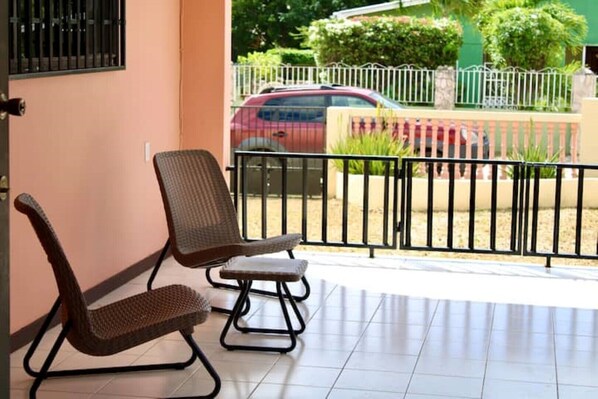 Un balcon avec deux fauteuils en osier et un sol carrelé.