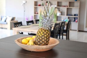 Un saladier en bois sur une table, avec un ananas et des citrons.