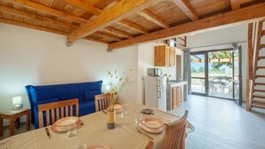 Een eetgedeelte met een houten tafel voor vier personen, een blauwe bank en een keuken op de achtergrond.