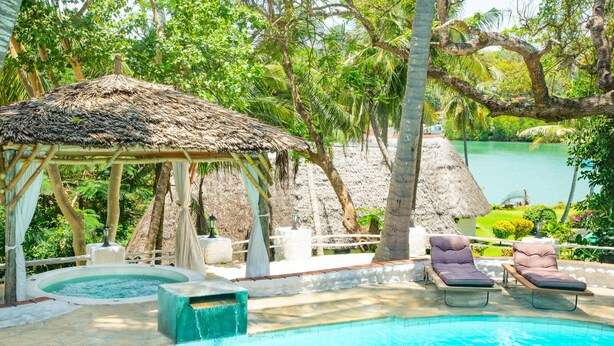 Un espace piscine comprenant des chaises longues, un jacuzzi et un kiosque.