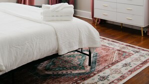 Une chambre à coucher avec un lit, un téléviseur posé sur une commode, un ventilateur de plafond et une fenêtre avec des rideaux.