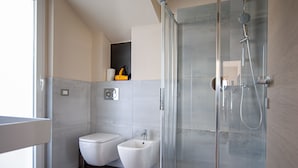 Een moderne badkamer met een douche met glazen wand, een toiletbrons en een toilet.