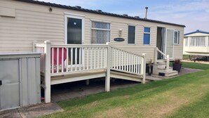 A mobile home with a porch, a small garden, and a neighboring trailer. - Chapel St Leonards Happy Days Beachfield (Mablethorpe)