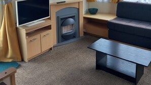 A room with a television, sofa, and a fireplace. - Chapel St Leonards Happy Days Beachfield (Mablethorpe)