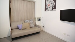 Un soggiorno moderno con un divano, cuscini, una televisione e un'opera d'arte appesa al muro.