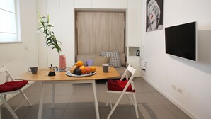 Un soggiorno moderno con un tavolo da pranzo, sedie, una TV e un divano.