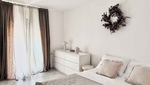 A bedroom with a bed, a nightstand, a dresser, and a wall-mounted wreath.