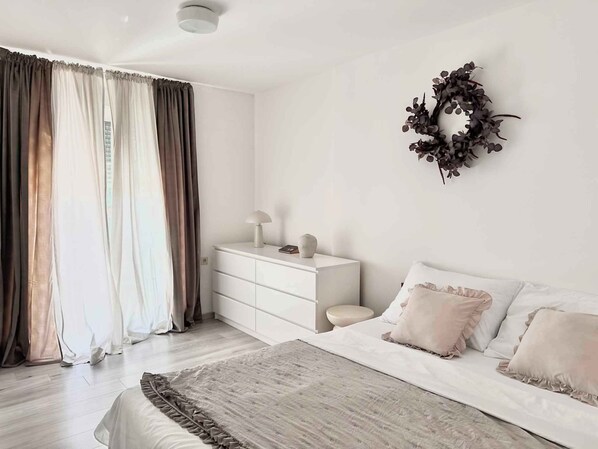 A bedroom with a bed, a nightstand, a dresser, and a wall-mounted wreath.