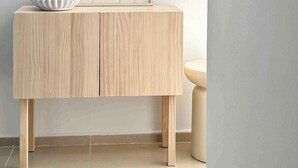 A minimalist room with a wooden console table, a framed artwork, a bowl, and a small stool.
