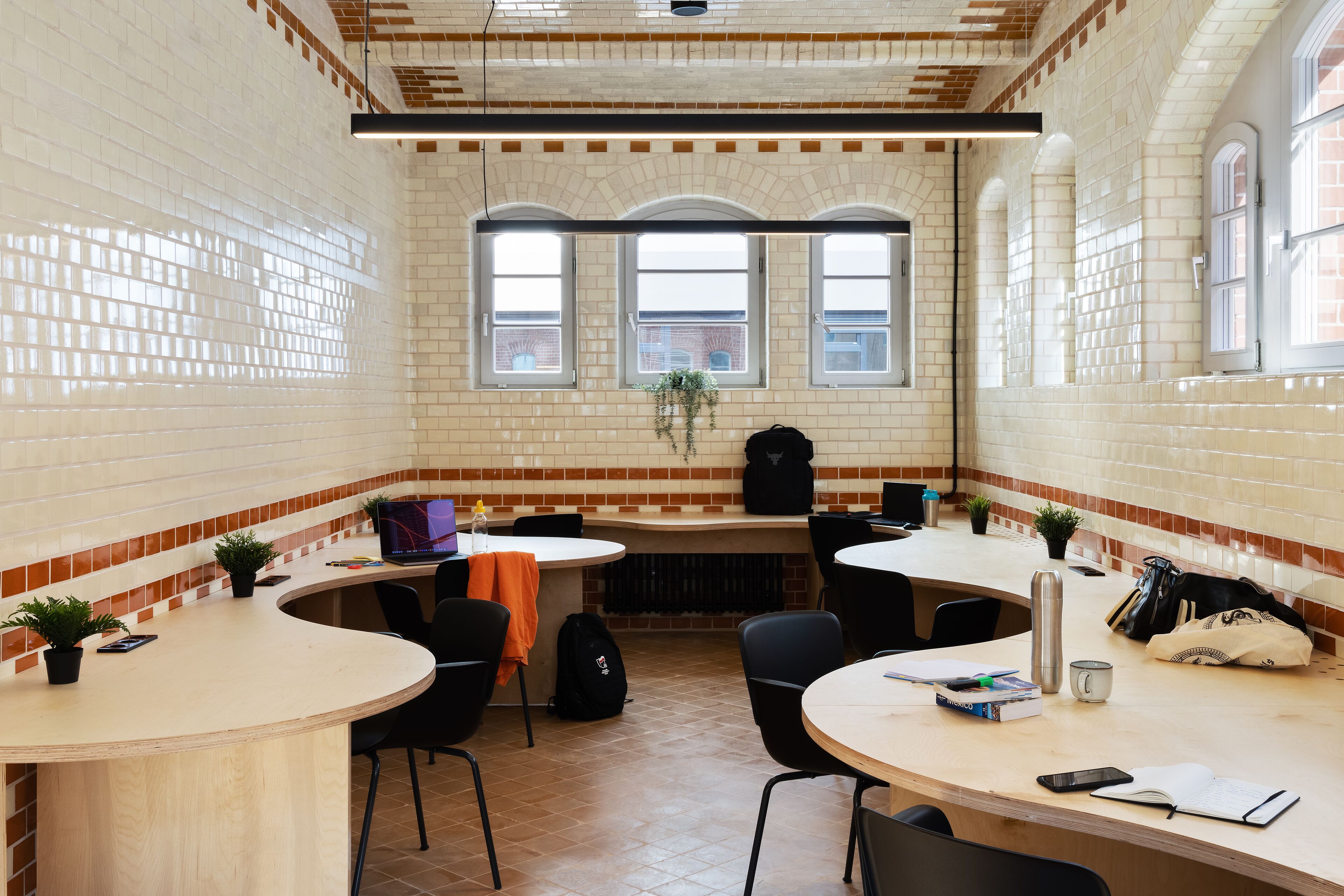 A modern kitchen with white and brown tiled walls, a brick ceiling, and large windows.