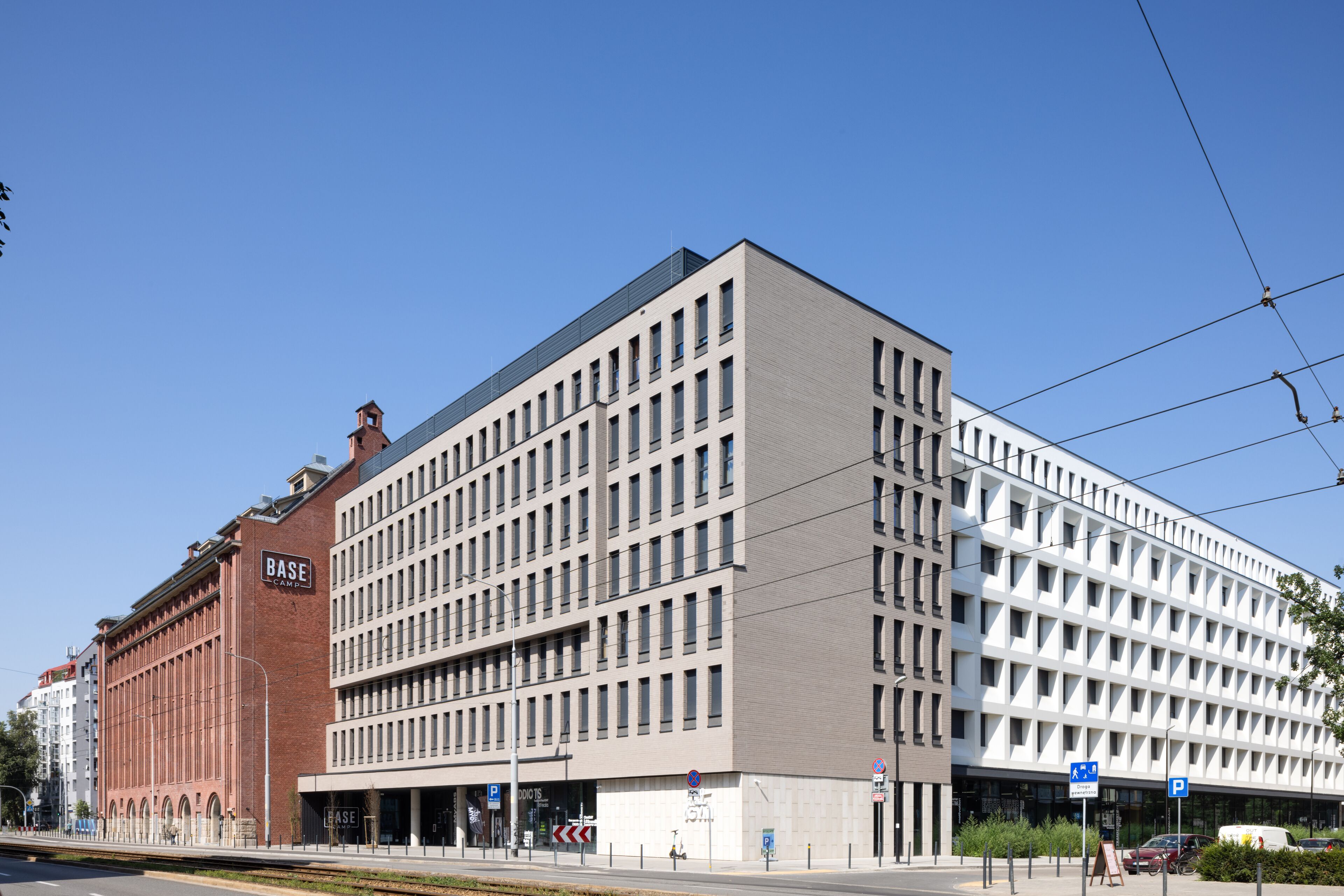 Un edificio moderno con un llamativo letrero que dice 'BASE', grandes ventanales y un cielo despejado.
