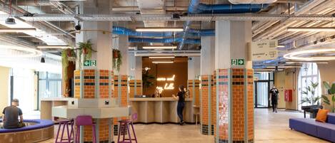 A modern indoor space with a reception desk, seating area, and directional signs.