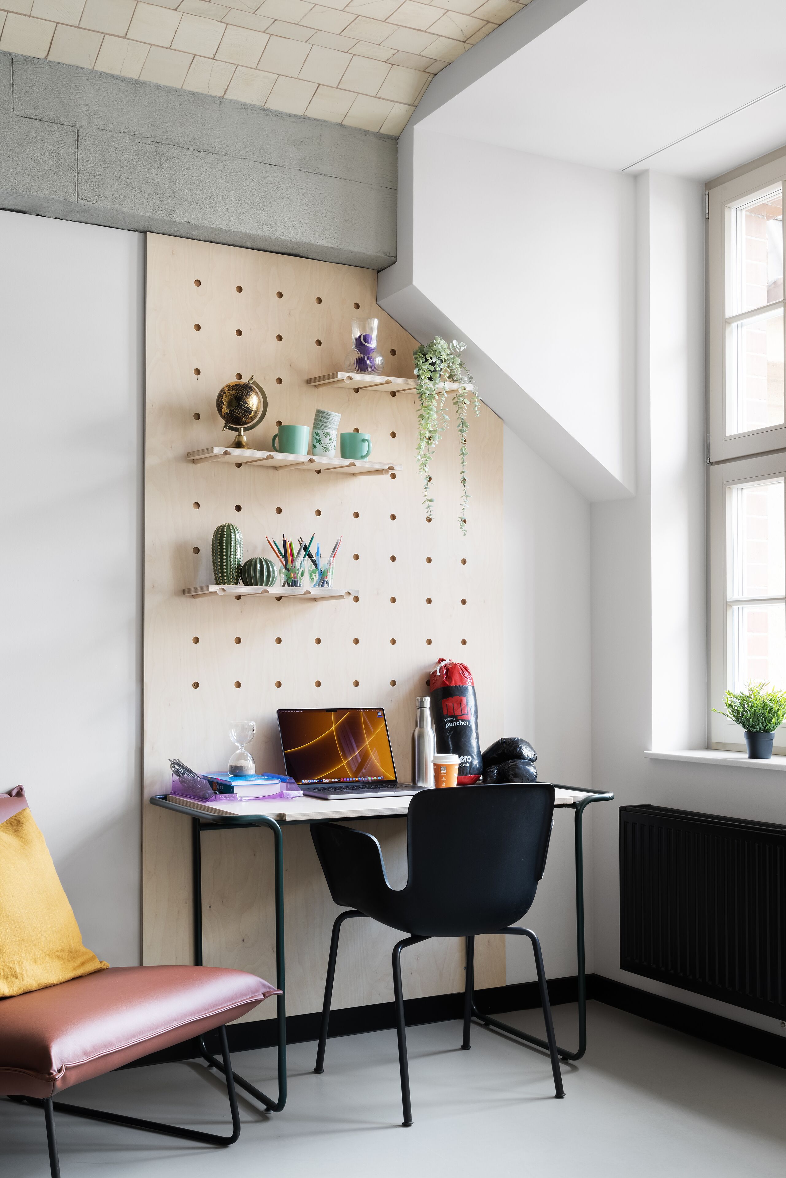 A modern workspace with a desk, chair, and shelving unit against a wall.