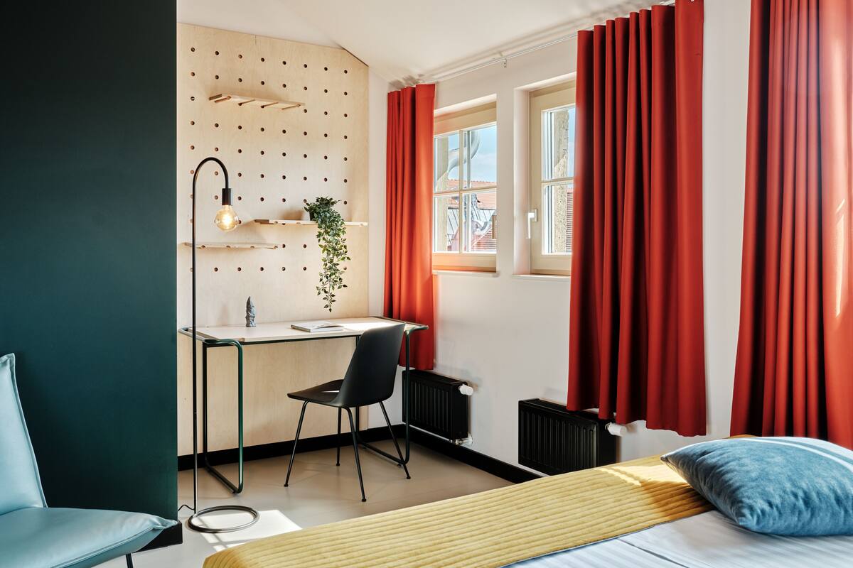 A modern bedroom with a bed, a desk, and a chair.