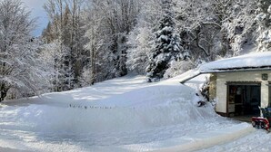 A snow-covered landscape with a mountain in the background, a path leading to a building with a garage, and a snow blower on the right. - Local tax 3 Eur Guest for Night (Semmering)