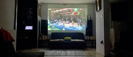 A living room with a large screen displaying a concert, a sofa, a coffee table, and a fireplace.