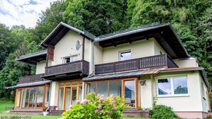 A two-story building with a balcony, large windows, and a garden with flowers. - Local tax 3 Eur Guest for Night (Semmering)