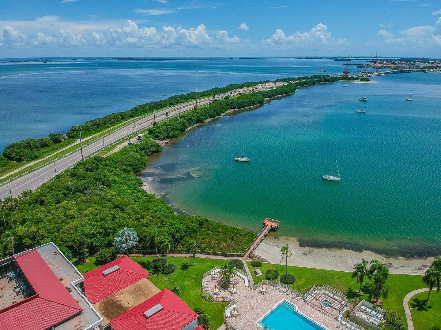Eine Luftaufnahme eines Küsteneigentums mit Schwimmbad, Strand und Booten im Wasser.