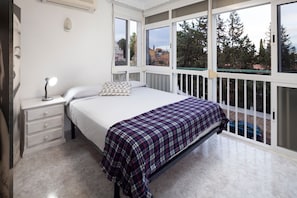 A bedroom with a bed, a bedside table with a lamp, a window, and a balcony. - Studio Apartment with Shared Pool, Wi-Fi and Air Conditioning (La Cala del Moral)