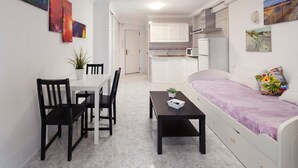 A compact living space with a dining area, kitchenette, and a bed.