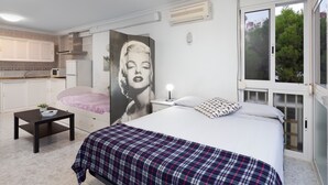 A bedroom with a bed, a bedside table, a nightstand, a poster, and a window.