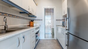 A narrow kitchen with white cabinets, a stainless steel sink, and a patterned door. - Holiday Apartment "Penthouse 3-Bedroom Duplex" with Sea View, Shared Pool & Wi-Fi (Mijas)