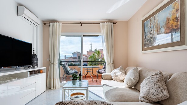 A modern living room with a flat-screen TV, a sofa, a coffee table, and a balcony with a table and chairs. - Holiday Apartment "Penthouse 3-Bedroom Duplex" with Sea View, Shared Pool & Wi-Fi (Mijas)