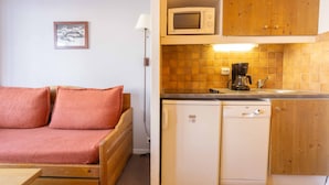 Una kitchenette compacta con microondas, cafetera y un refrigerador pequeño.