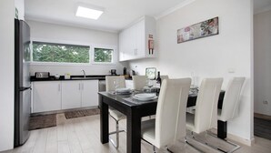 A modern kitchen with white cabinets, a black dining table, and four chairs.