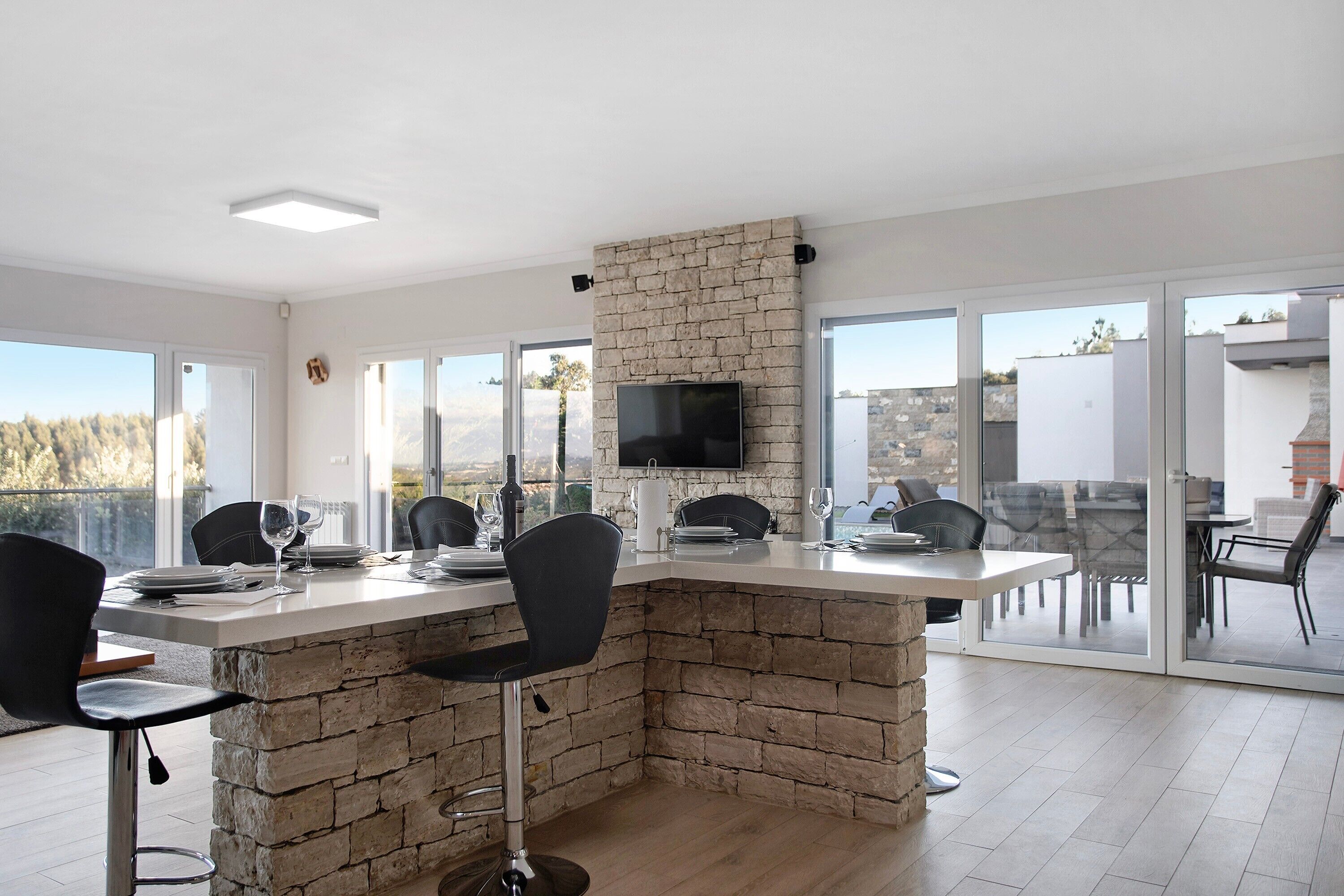 Una cocina moderna con una isla de piedra, un televisor de pantalla plana y una zona de comedor con sillas y una mesa.